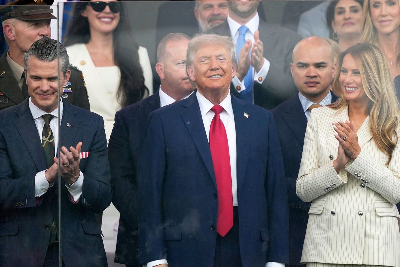 Donald Trump (Mitte) und First Lady Melania Trump sowie Verteidigungsminister Pete Hegseth (l.) sehen sich die Parade zum 250. Geburtstag der US-Armee an.