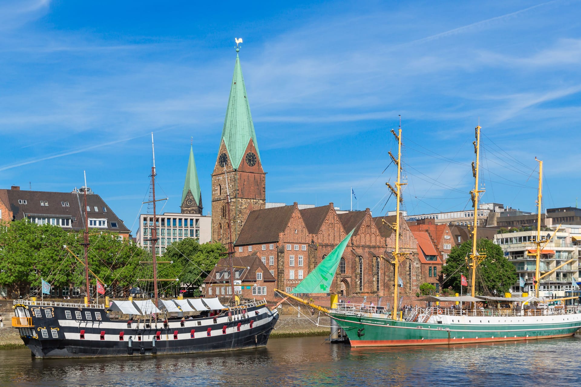 Cityscape of Bremen with old architecture, historical wooden sailing ships and barge floating along the river Weser. Bremen, Germany, July 15, 2021