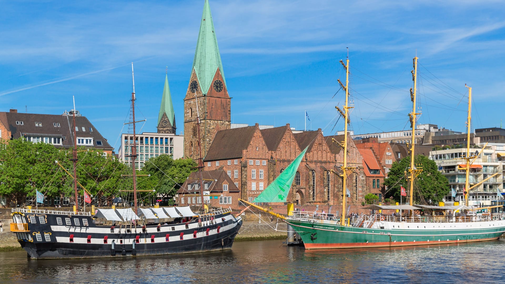 Cityscape of Bremen with old architecture, historical wooden sailing ships and barge floating along the river Weser. Bremen, Germany, July 15, 2021