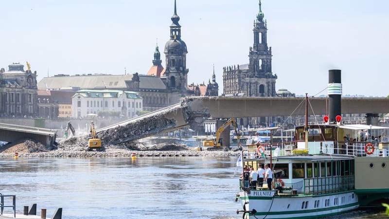 Mit schweren Baugeräten werden die Brückenteile A und B der Carolabrücke abgerissen während im Vordergrund der Dampfer «Pillnitz» der Sächsischen Dampfschifffahrt Weiße Flotte am Ufer anlegt.