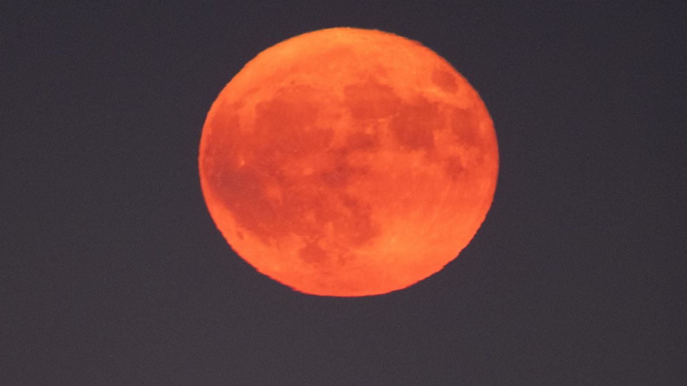 Der Erdbeermond leuchtet in rot-orangen Farben.