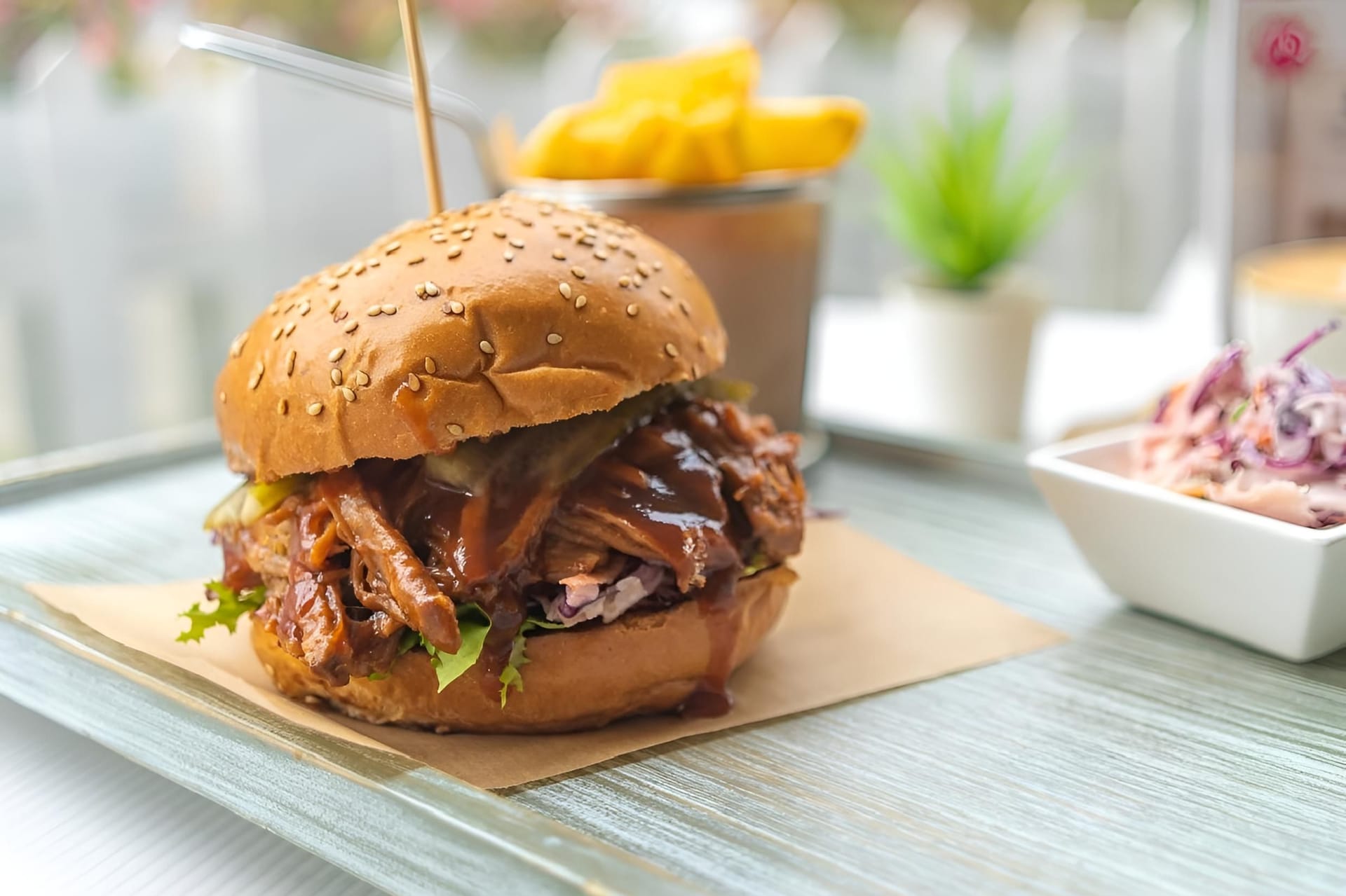 a delicious pulled pork burger with fries and coleslaw on a tray in a casual dining setting.