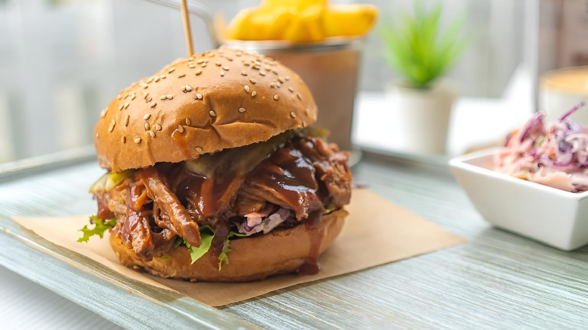 a delicious pulled pork burger with fries and coleslaw on a tray in a casual dining setting.