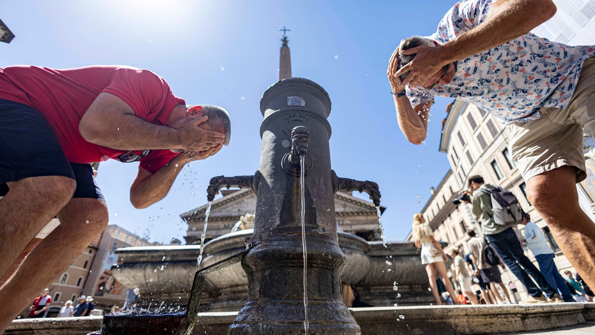Sommer in Rom: Zwei Männer erfrischen sich an einem öffentlichen Wasserspender. Sommer in Rom: Zwei Männer erfrischen sich an einem öffentlichen Wasserspender.