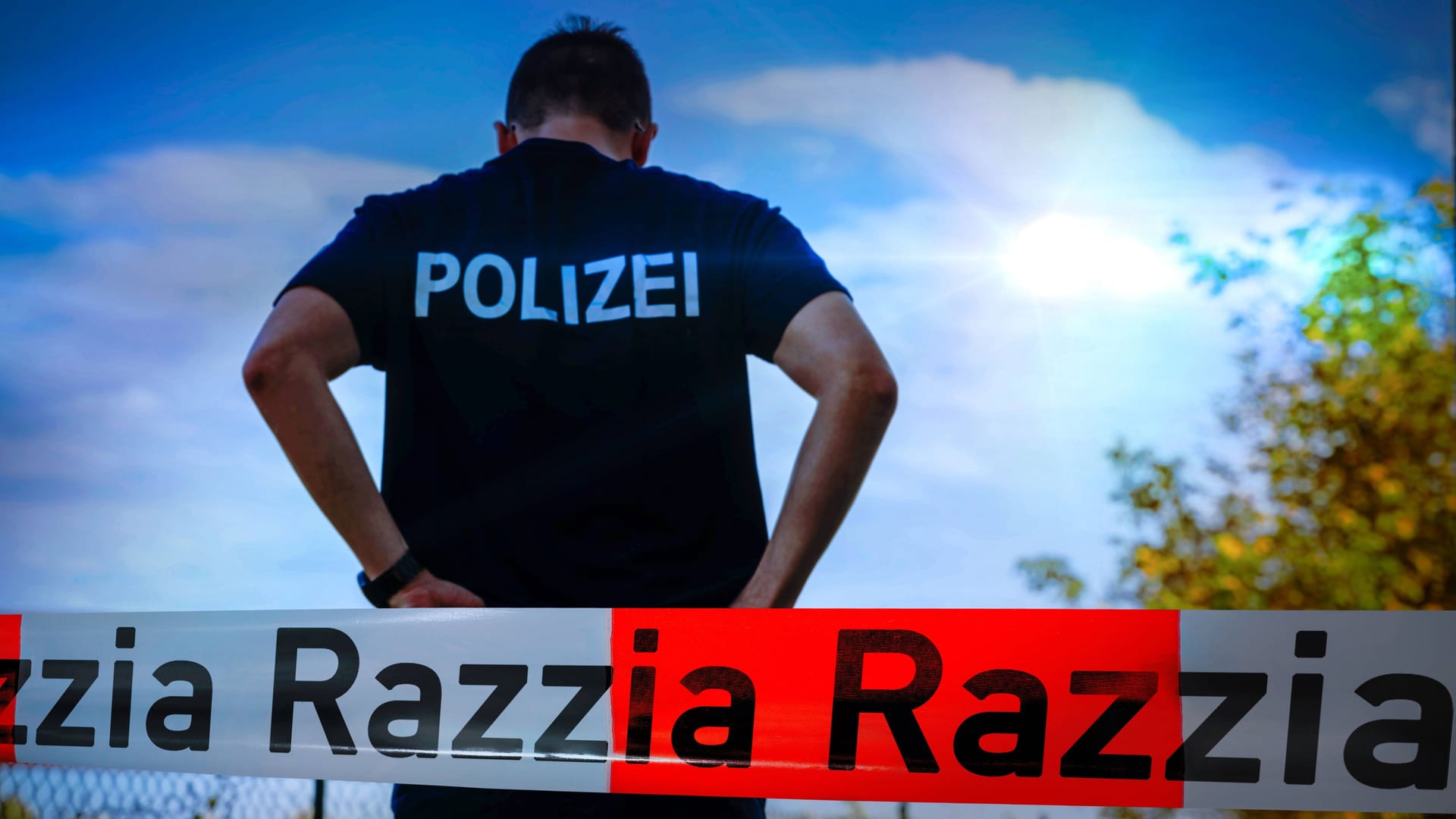 Ein Polizeibeamter steht hinter einem Absperrband (Archivbild): Die Aktion läuft seit dem frühen Mittwochmorgen in allen 16 Bundesländern.