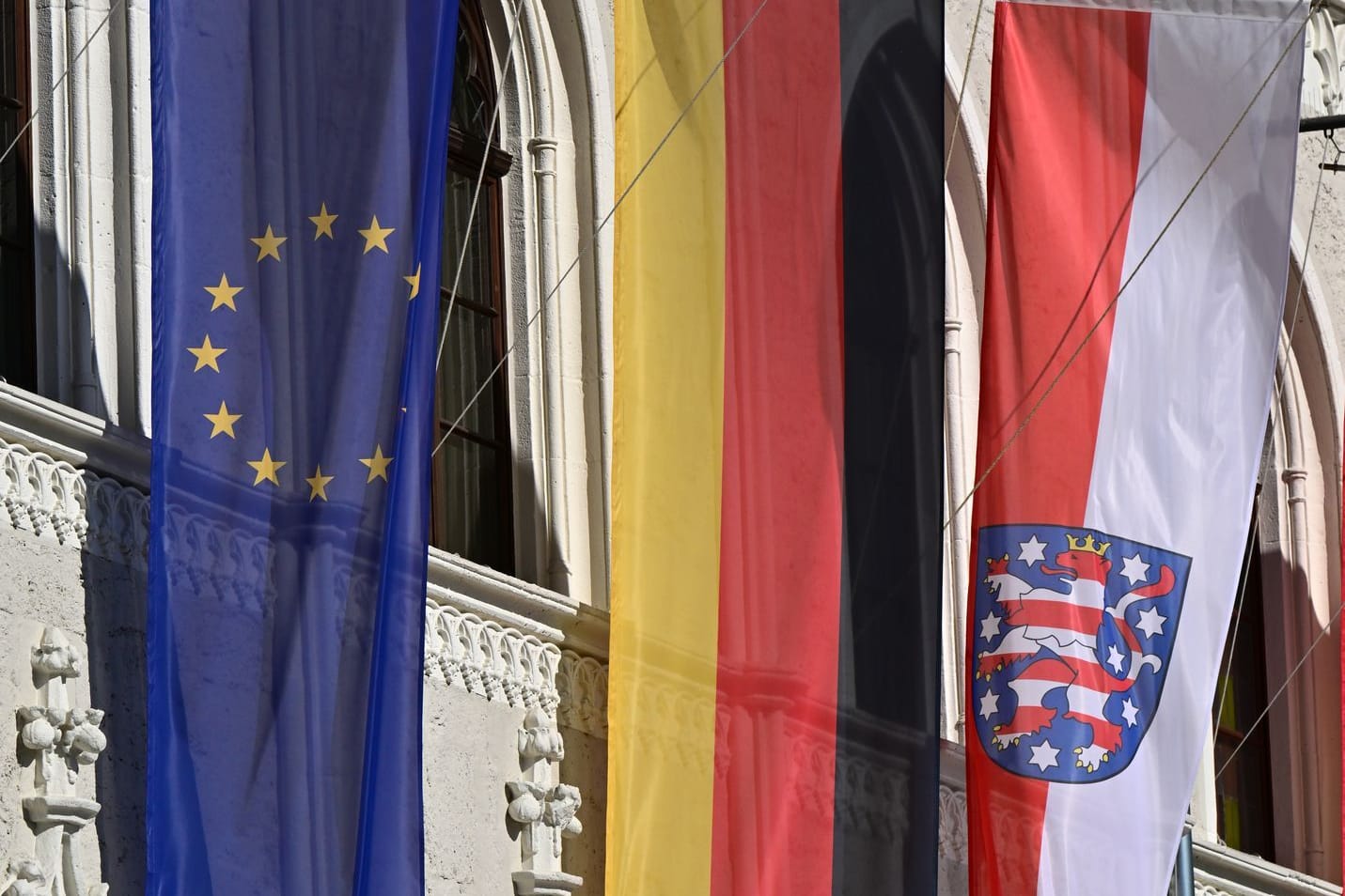 Fahnen für Europa, Deutschland und Thüringen wehen vor dem historischen Weimarer Rathaus am Markt.