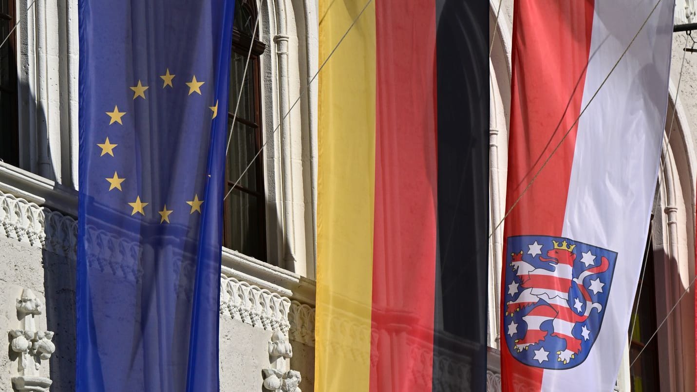 Fahnen für Europa, Deutschland und Thüringen wehen vor dem historischen Weimarer Rathaus am Markt.