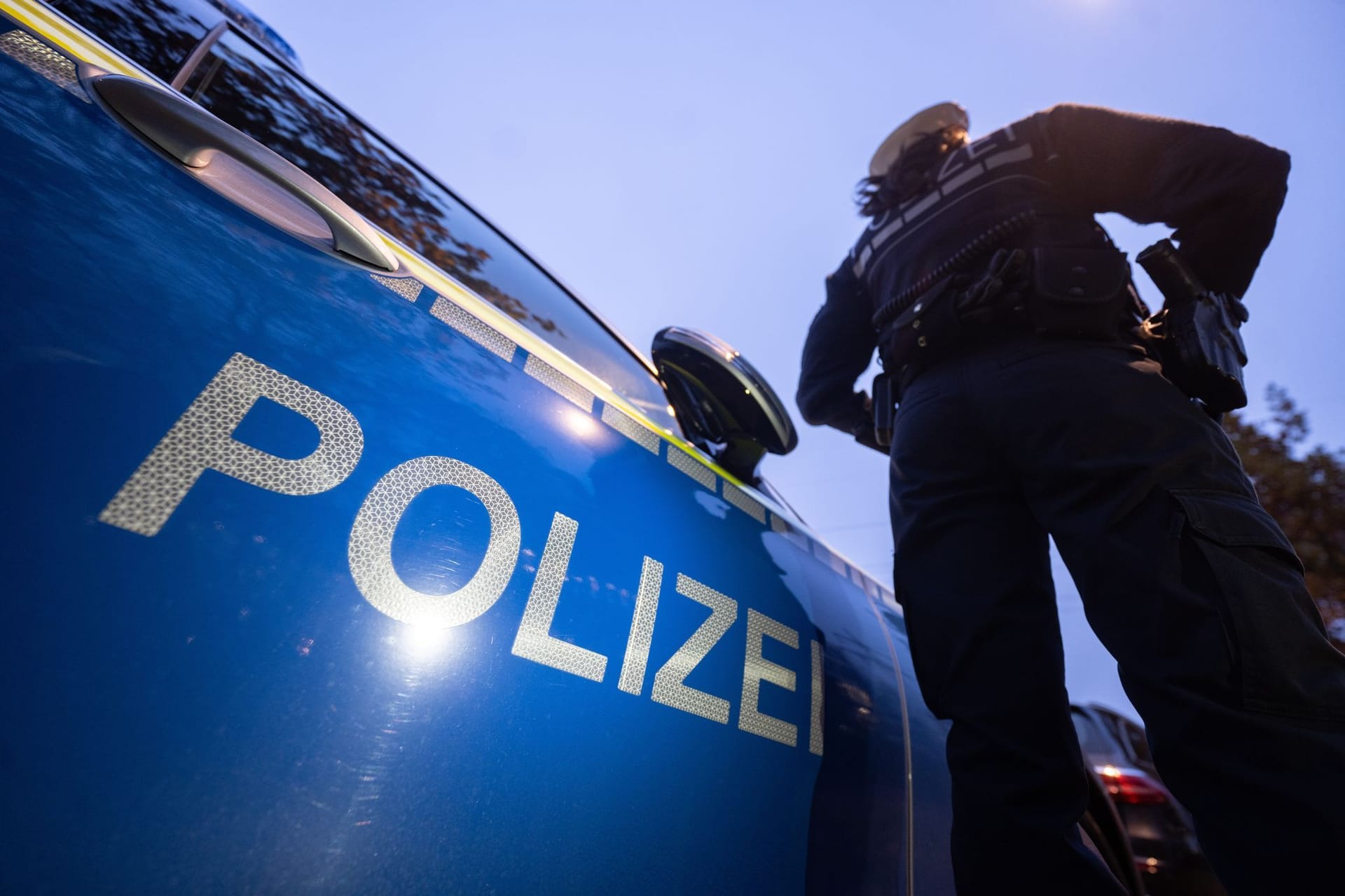 Eine Polizistin steht neben einem Polizeifahrzeug: Bei einem Schusswechsel an der deutsch-tschechischen Grenze ist am Freitag ein Mann ums Leben gekommen.