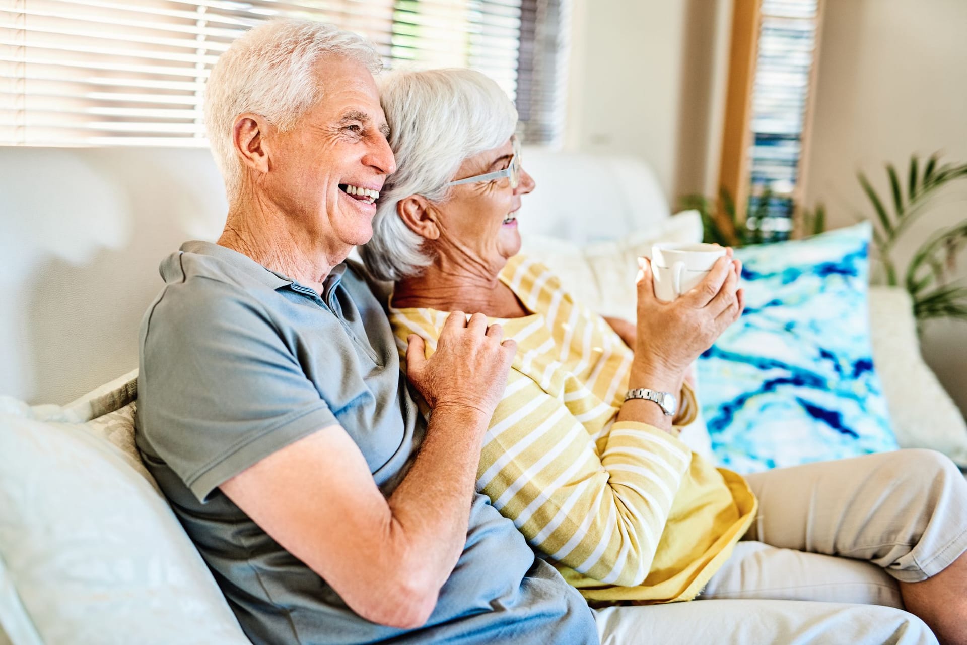 Glückliches Rentnerpaar sitzt zu Hause auf dem Sofa.