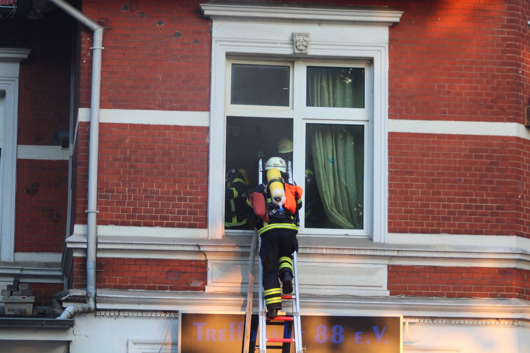Durch das Fenster ins Feuer: Einsatzkräfte verschaffen sich Zugang zum brennenden Haus.