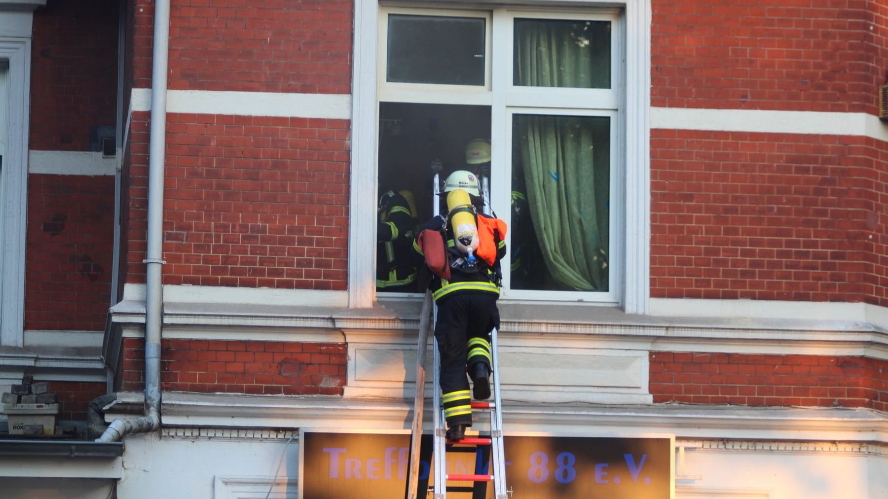 Durch das Fenster ins Feuer: Einsatzkräfte verschaffen sich Zugang zum brennenden Haus.