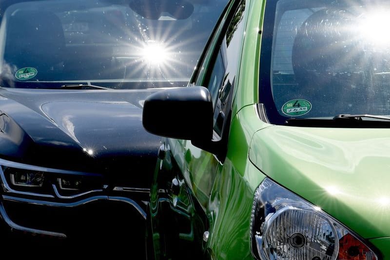 Sonne scheint auf zwei Autos (Symbolbild): Im Sommer kann es im Auto schnell gefährlich heiß werden.