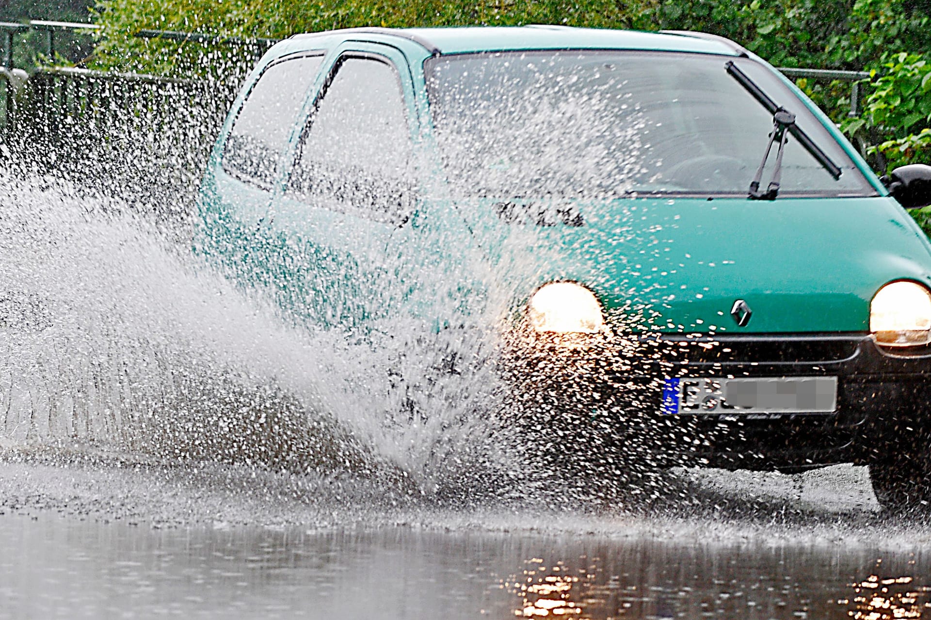 Auto pflügt durch eine Pfütze (Symbolfoto): Im Ruhrgebiet werden statt des mancherorts befürchteten Starkregens eher kleinere Schauer erwartet.