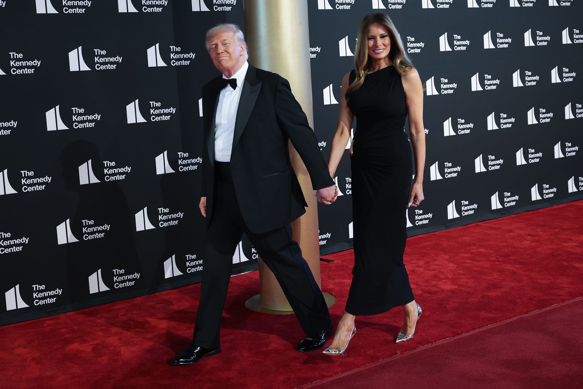 Donald und Melania Trump Hand in Hand auf dem roten Teppich.