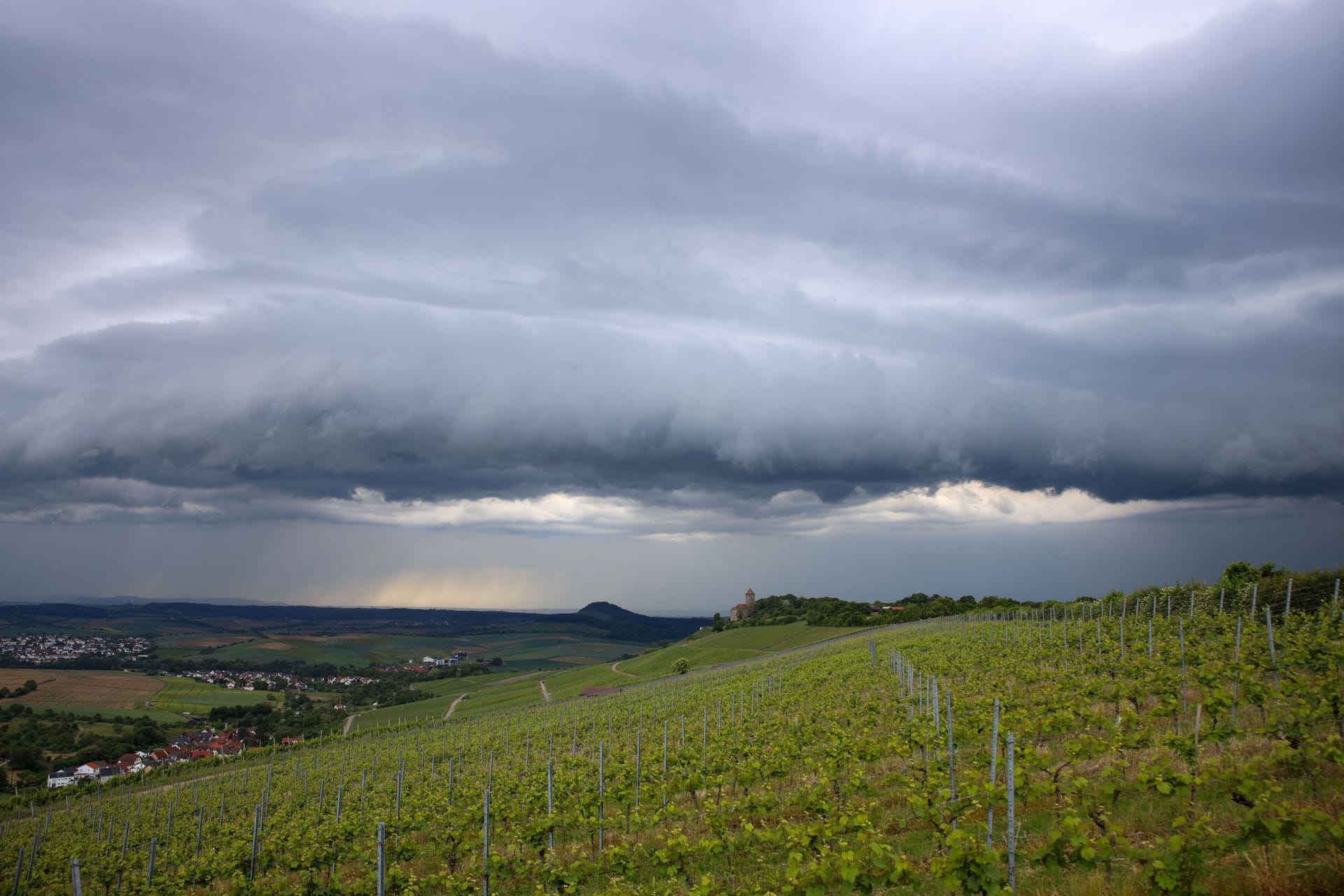 Baden-Württemberg, Oberstenfeld: Eine dunkle Gewitterwolke zieht hinter den Weinbergen bei Oberstenfeld im Landkreis Ludwigsburg auf.