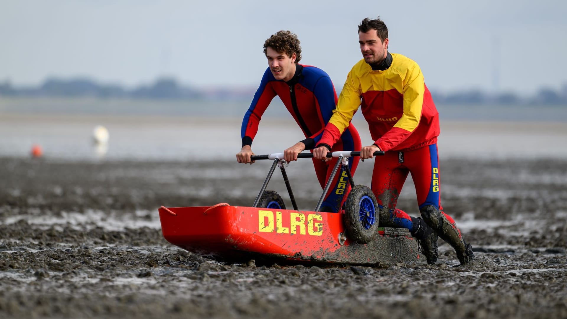 Jonathan Ommerborn (l) und Sven Gärtner von der DLRG-Ortsgruppe Varel erproben den neuen Schlickschlitten für Rettungseinsätze in Dangast.