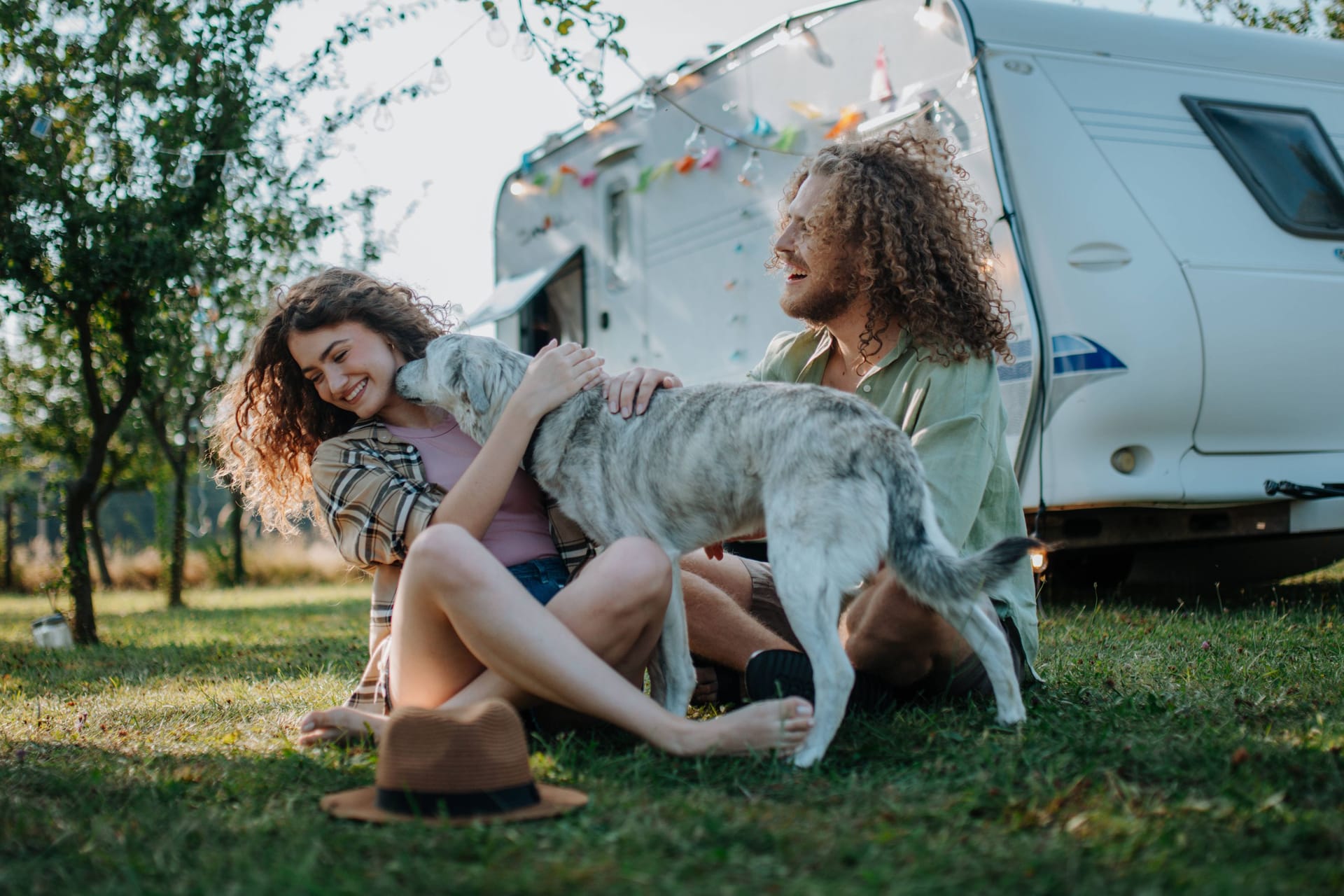 Paar mit Hund und Campingwagen: Auf manchen Campingplätzen werden Hunde toleriert, auf anderen sind sie willkommen.