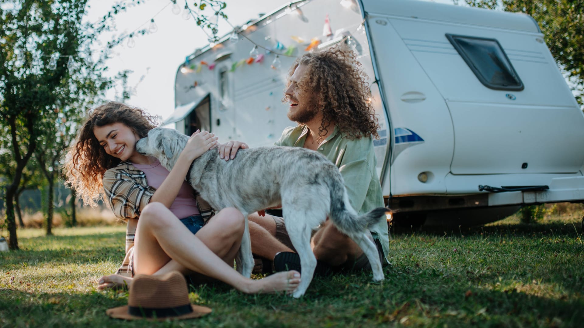 Paar mit Hund und Campingwagen: Auf manchen Campingplätzen werden Hunde toleriert, auf anderen sind sie willkommen.