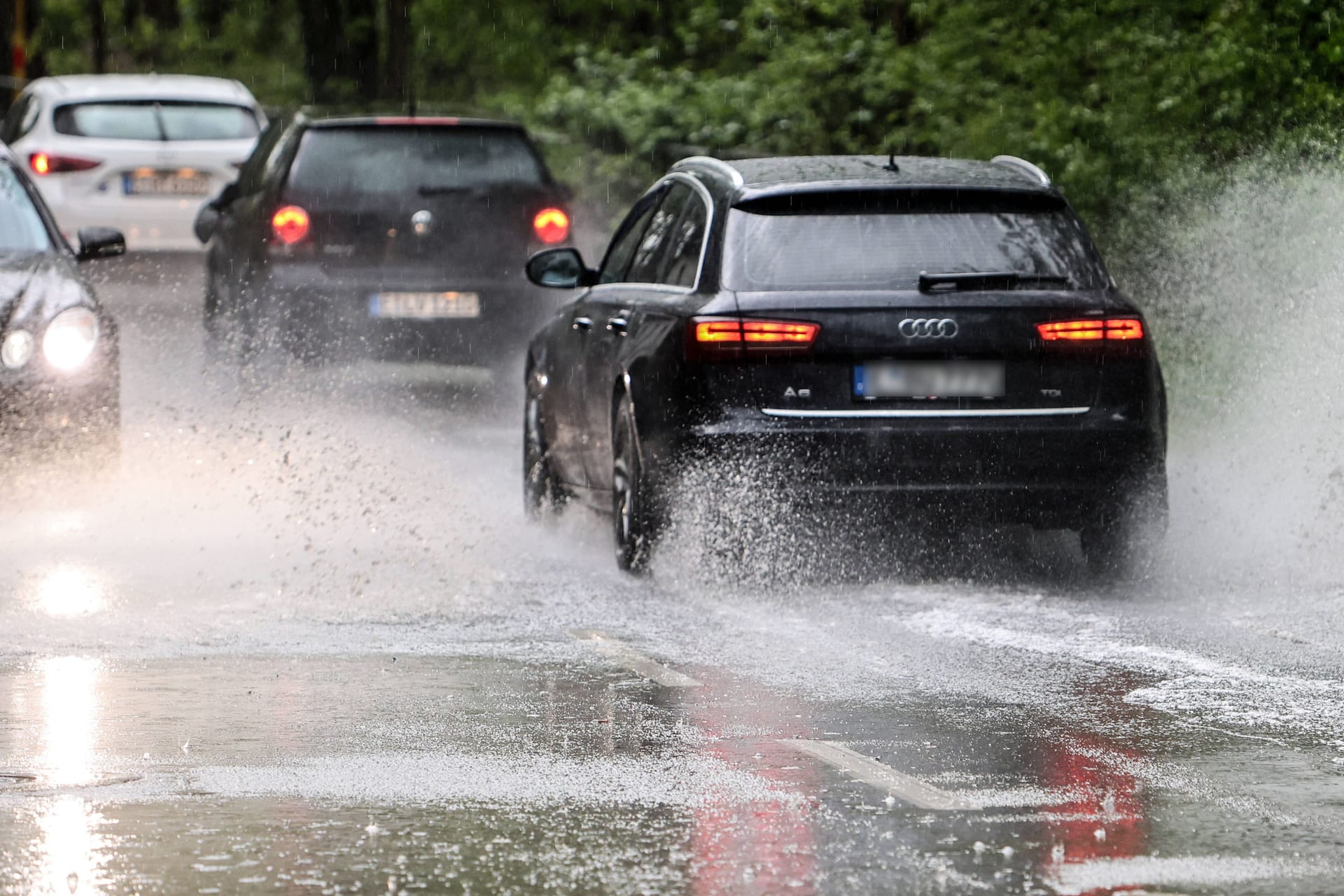 Autos fahren über eine überflutete Straße (Symbolbild): In Köln und der Region werden am Wochenende Starkregen und Unwetter erwartet.