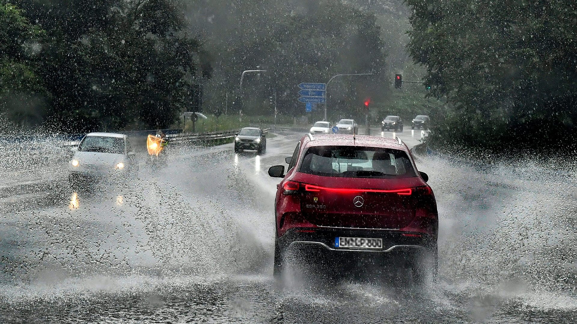Autos während starker Regenfälle auf einer Straße (Archivbild): An Pfingsten drohen in Köln und der Region erneut starke Schauer und Gewitter.