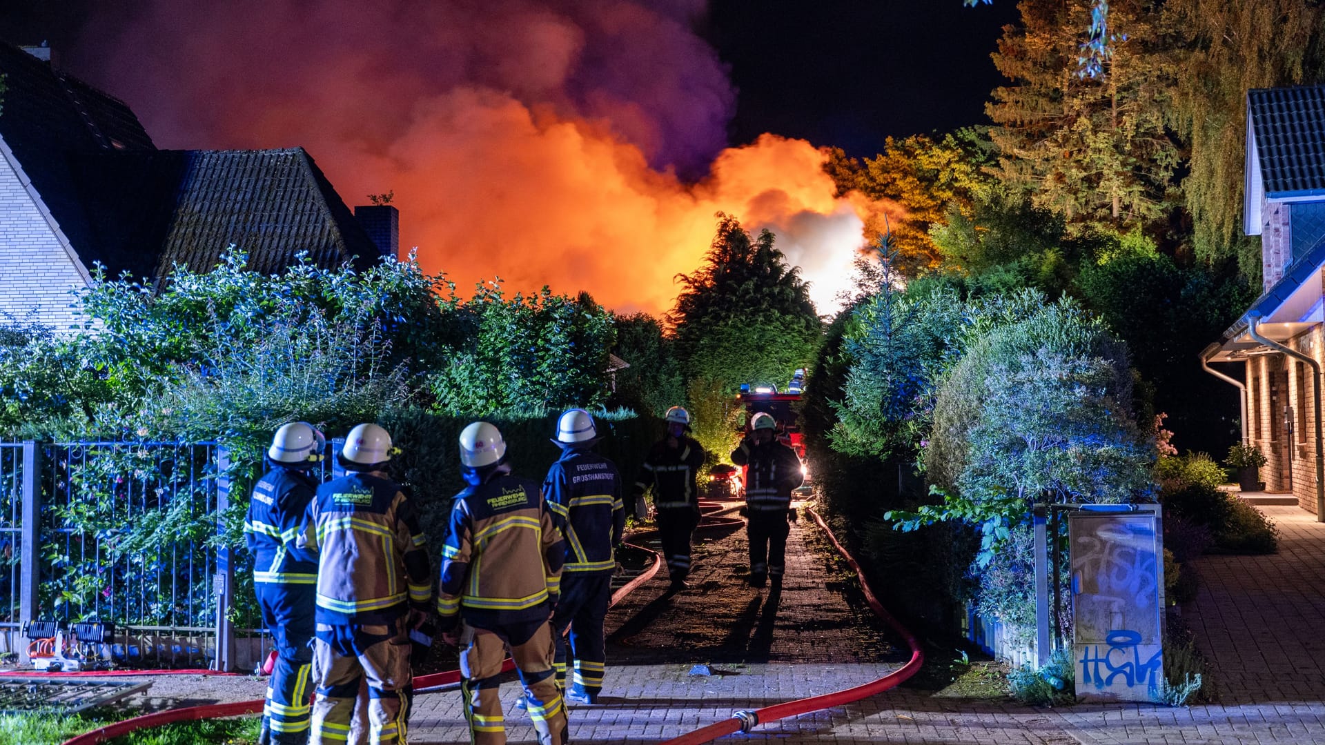 Feuerwehrleute stehen vor dem brennenden Haus: Der Feuerschein war weit am Nachthimmel in Großhansdorf zu sehen.