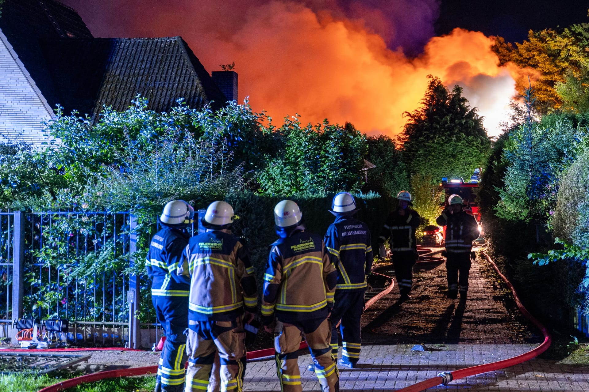 Feuerwehrleute stehen vor dem brennenden Haus: Der Feuerschein war weit am Nachthimmel in Großhansdorf zu sehen.