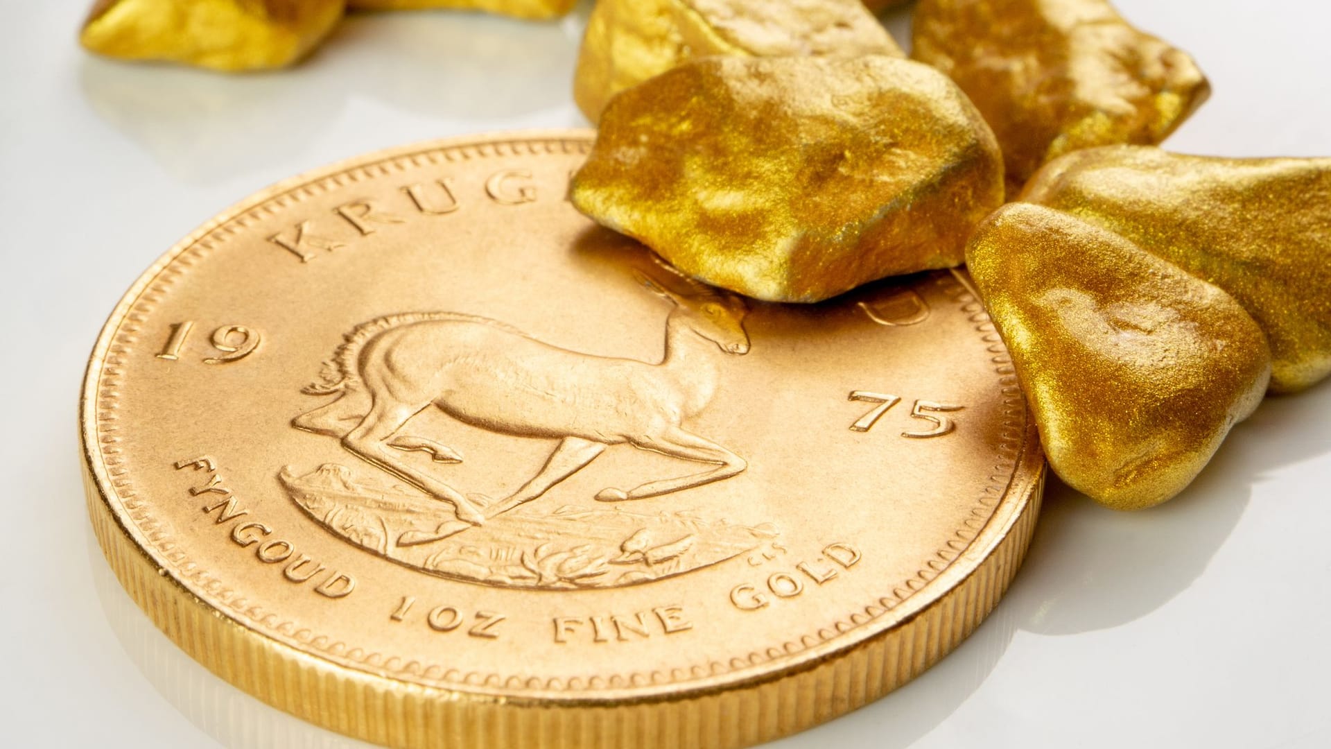 Goldene südafrikanische Krügerrand 1 Unze Münze auf einem Haufen von goldenen Nuggets
