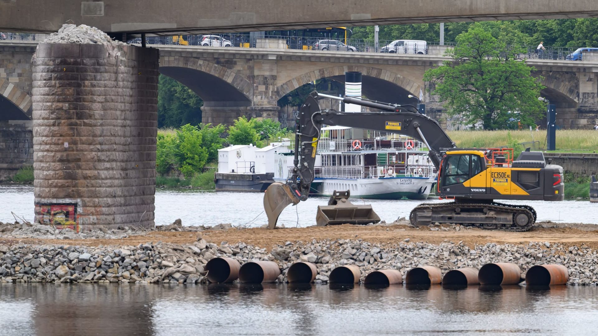 Ein Bagger steht auf einer Baustraße vor dem noch stehen Brückenzug der Carolabrücke, im Hintergrund ist eine Dampfer der Sächsischen Dampfschifffahrt Weiße Flotte zu sehen. Ein Teil der 1971 in Betrieb genommenen Brücke mit Straßenbahngleisen und Radweg war in der Nacht zum 11. September 2024 völlig überraschend eingestürzt. Ein Bagger steht auf einer Baustraße vor dem noch stehen Brückenzug der Carolabrücke, im Hintergrund ist eine Dampfer der Sächsischen Dampfschifffahrt Weiße Flotte zu sehen. Ein Teil der 1971 in Betrieb genommenen Brücke mit Straßenbahngleisen und Radweg war in der Nacht zum 11. September 2024 völlig überraschend eingestürzt.