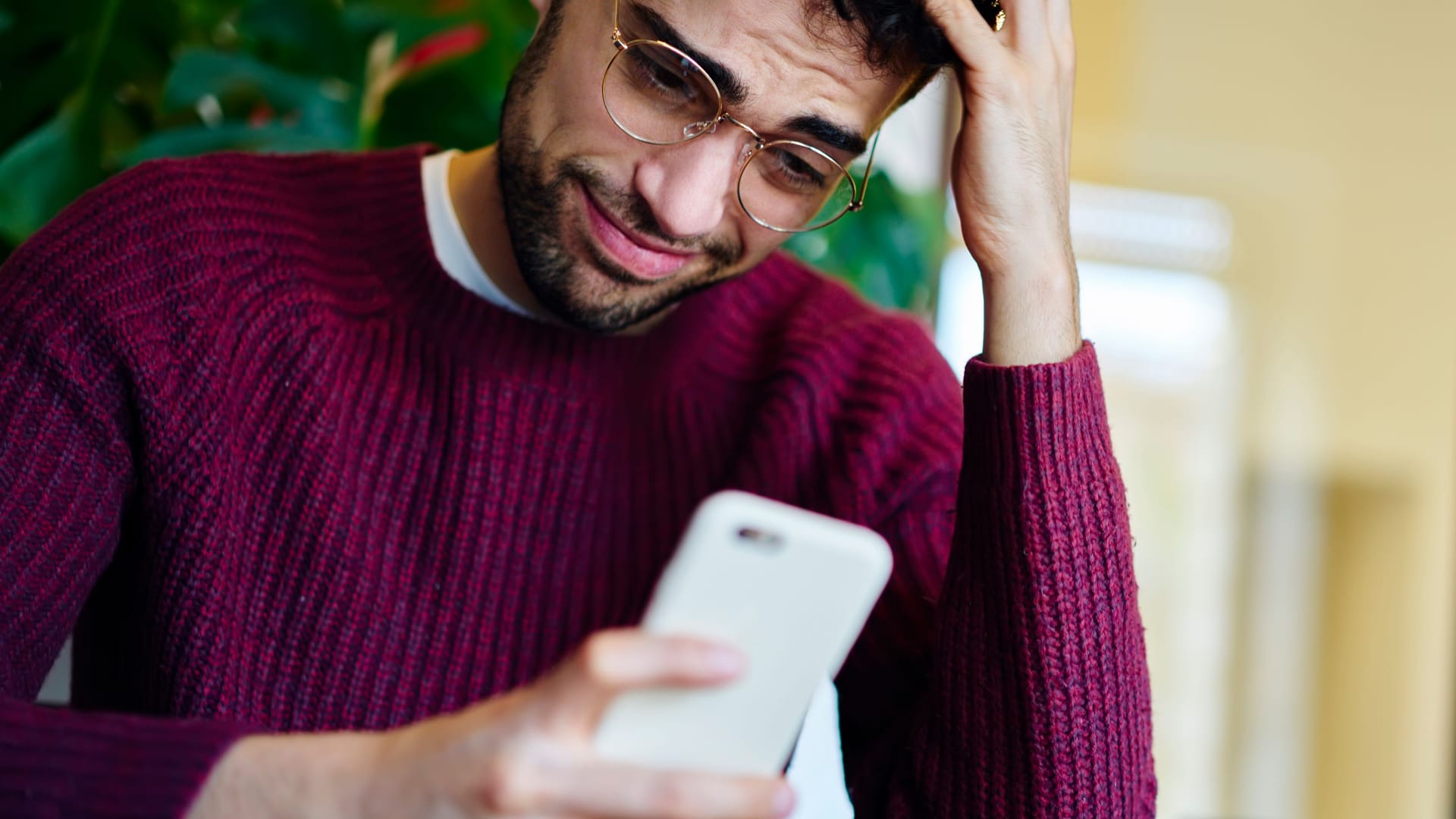 Ein Mann blickt grübelnd auf sein Smartphone