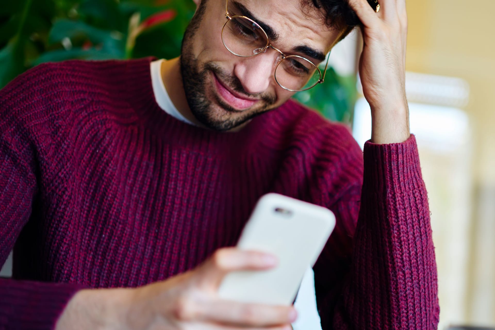Ein Mann blickt grübelnd auf sein Smartphone