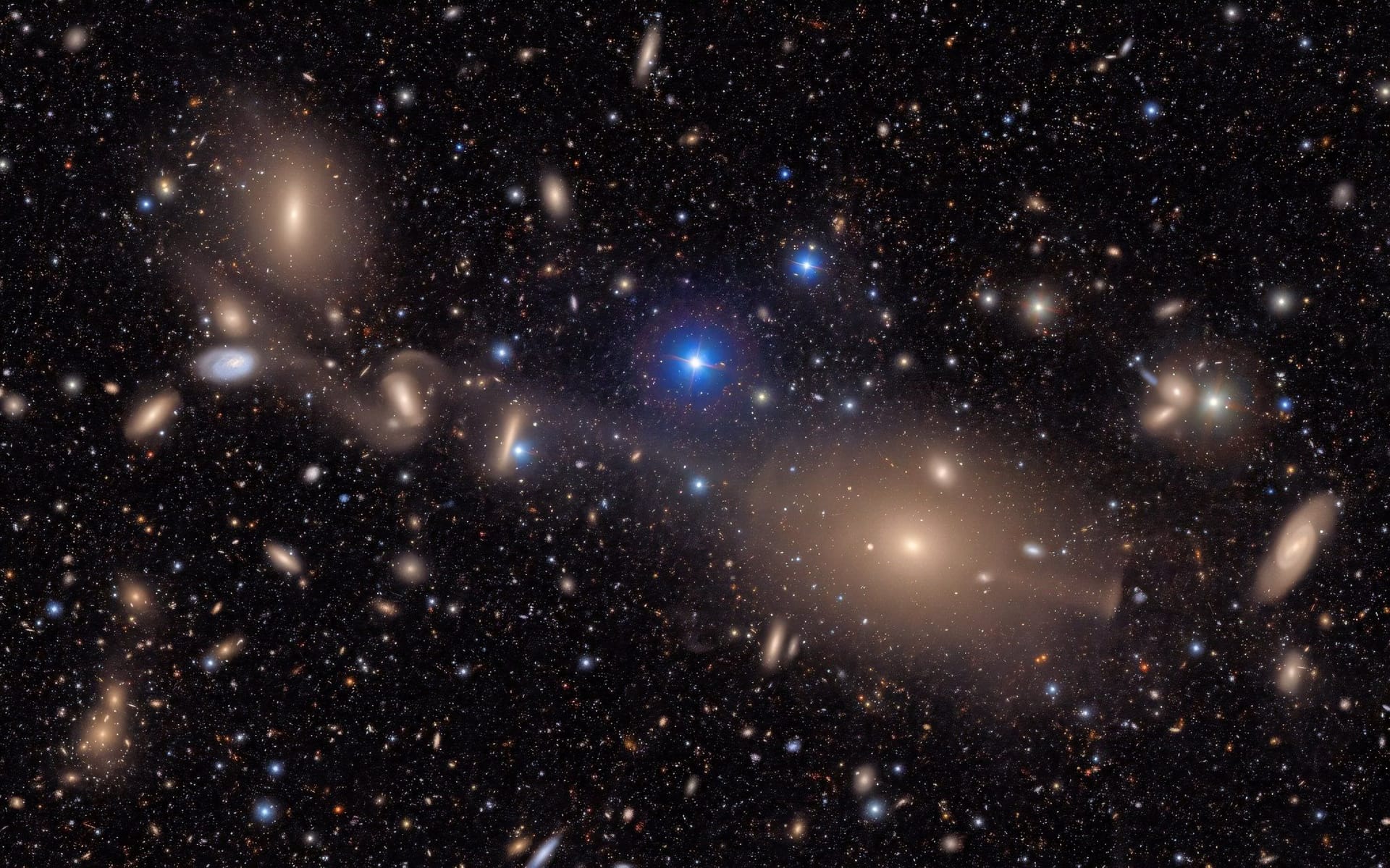 In dem Ausschnitt aus einer größeren Aufnahme des Virgo-Haufens leuchten helle Sterne im Vordergrund vor zahlreichen fernen Galaxien.