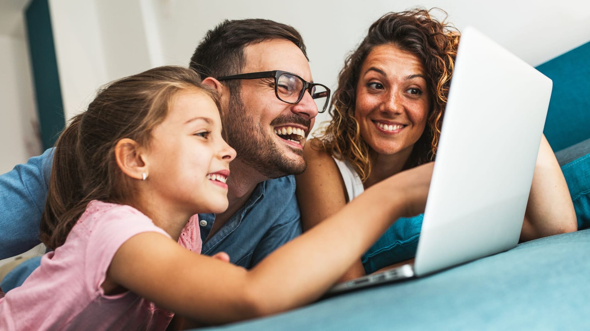 Familie liegt auf dem Bett und schaut auf einen Laptop-Bildschirm Familie liegt auf dem Bett und schaut auf einen Laptop-Bildschirm