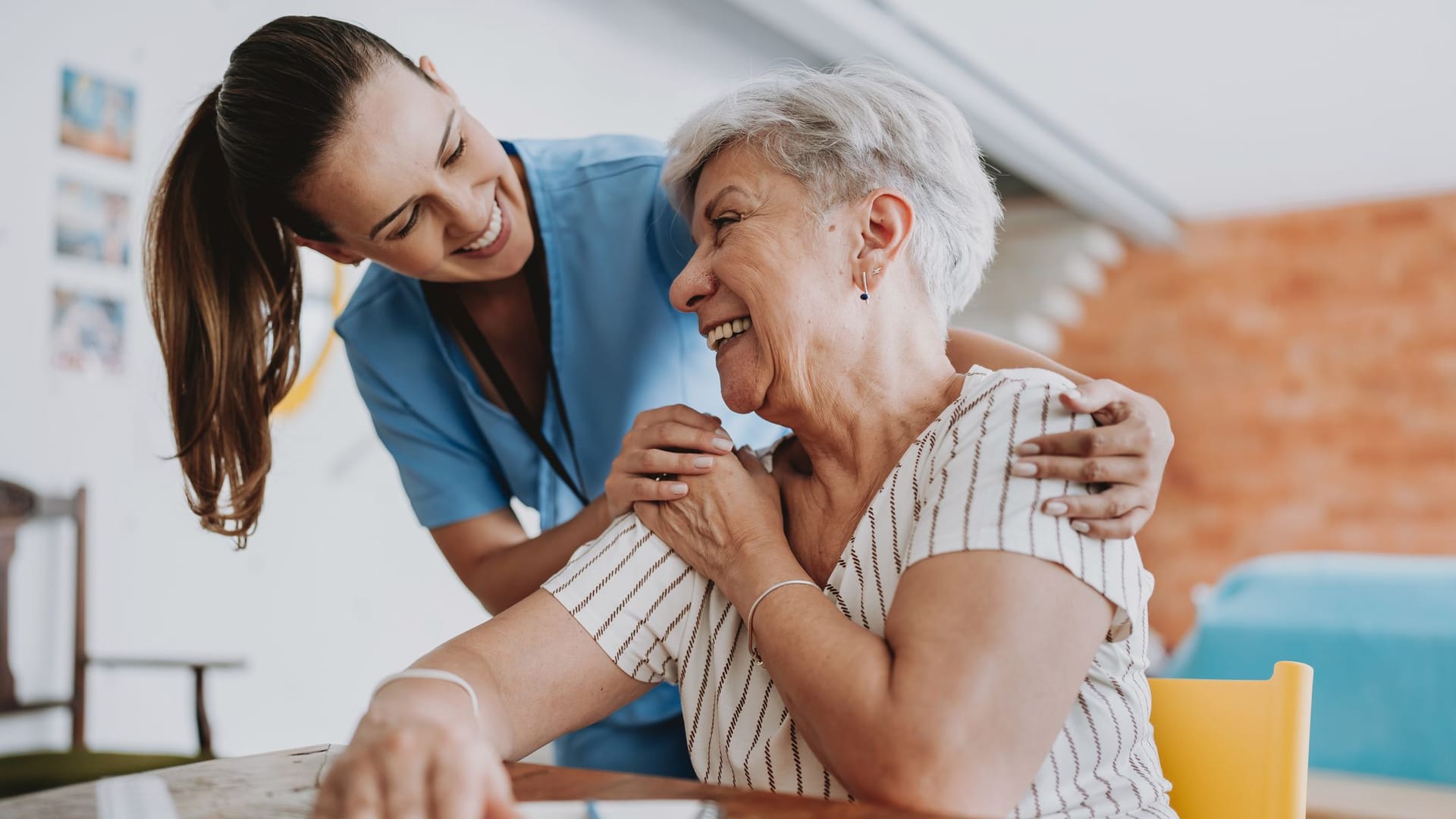 Pflegerin unterstützt eine Seniorin zu Hause