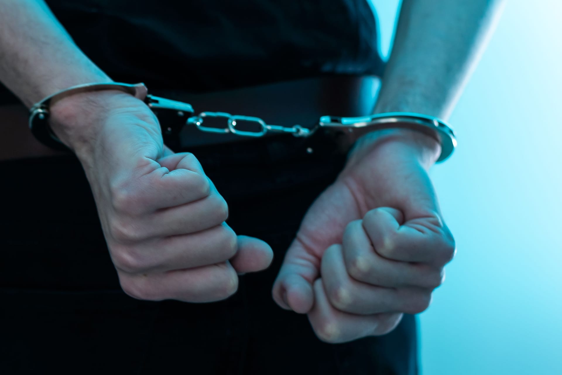 Arrested man handcuffed hands at the back. prisoner concept, Handcuffed hands of a prisoner in prison, Male prisoners were severely strained in the dark prison, violence, handcuffed hands is strapped