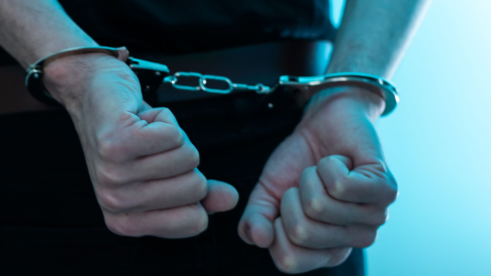 Arrested man handcuffed hands at the back. prisoner concept, Handcuffed hands of a prisoner in prison, Male prisoners were severely strained in the dark prison, violence, handcuffed hands is strapped