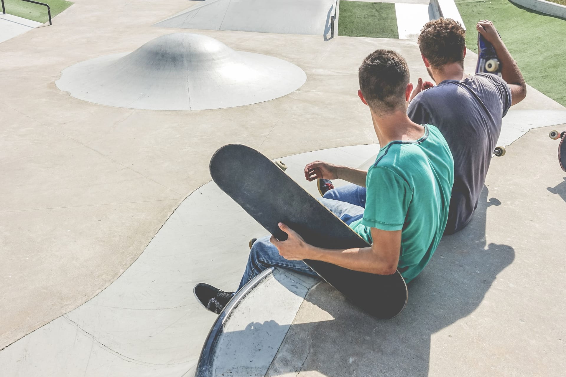 Teenagers performing with skateboard in city skate park - Young skaters doing tricks and skills outdoor - Extreme sport, youth lifestyle and friendship concept - Focus on close-up guy