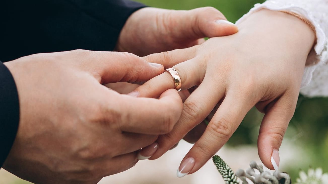 Bräutigam steckt Braut den Ehering an den Finger
