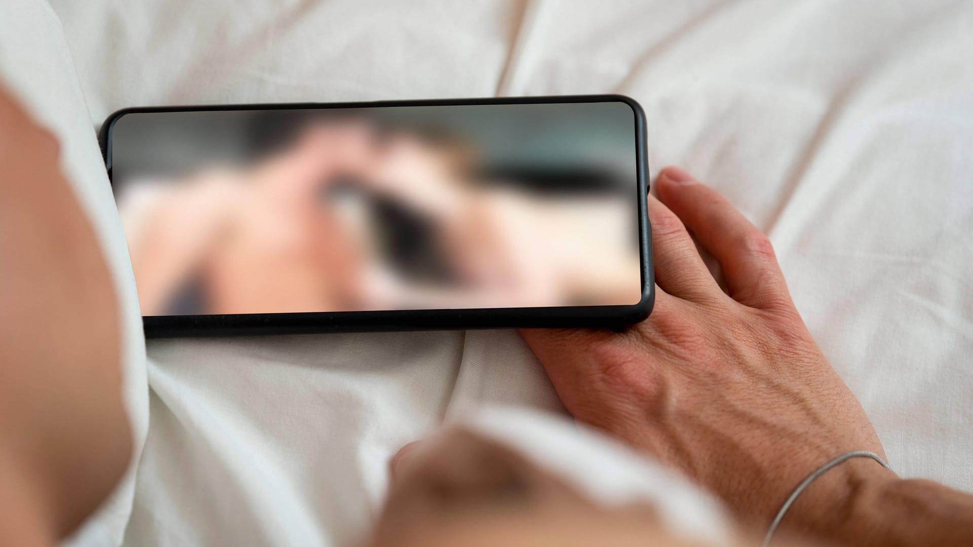 Ein Mann liegt im Bett und schaut einen Porno (Symbolbild): Eine britische Politikerin forder strengere Regulierungen für Sexfilme.