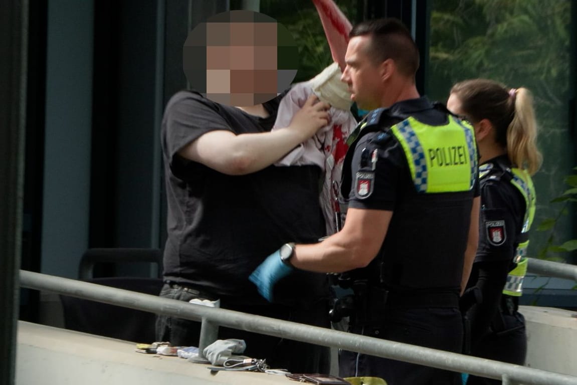 Polizeibeamte kümmern sich um einen blutenden Mann: Bei einem Messerstreit in Hamburg-Harburg wurden zwei Menschen verletzt, eine Frau schwer.