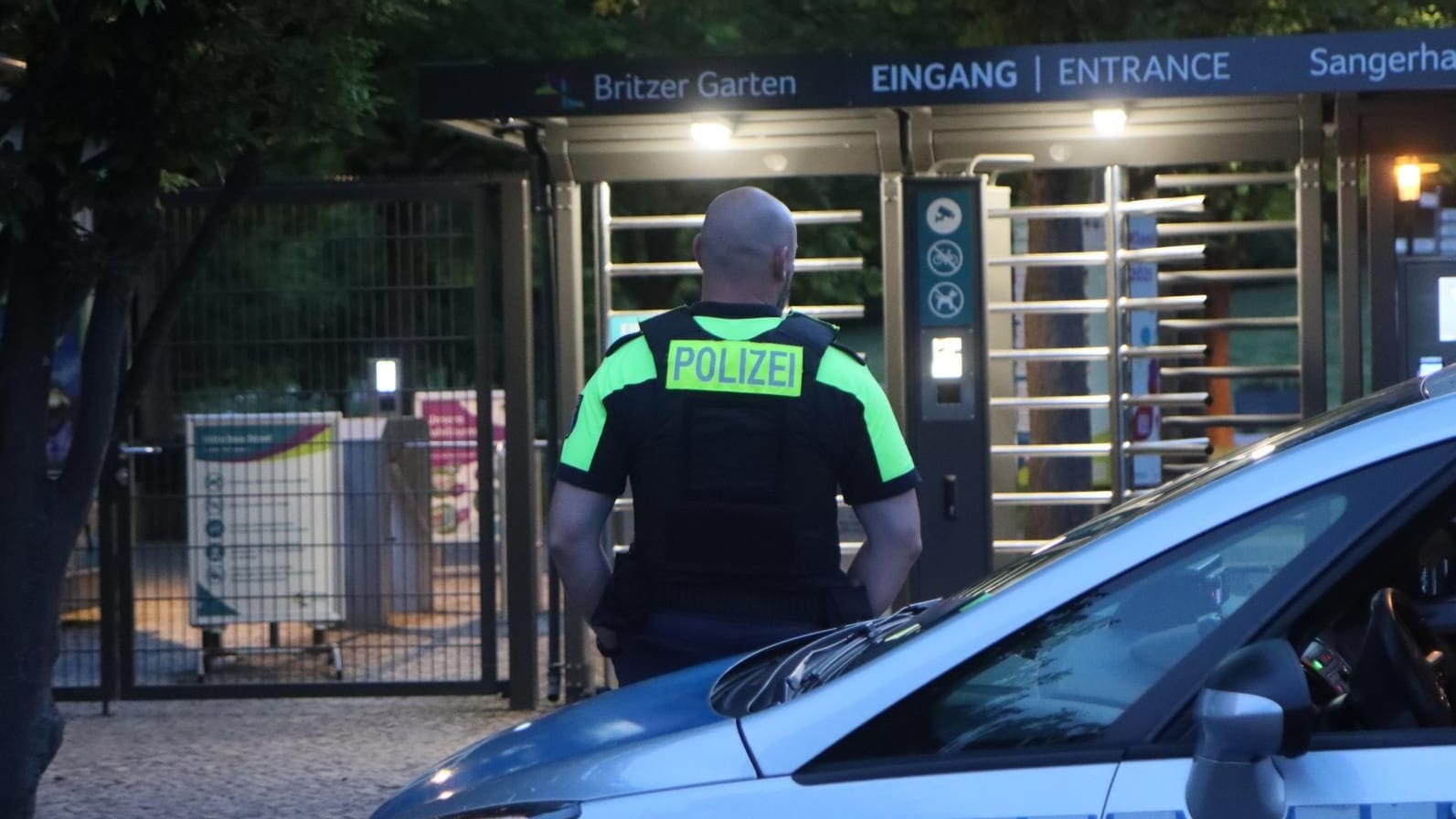 Ein Polizeibeamter steht vor einem Streifenwagen am Britzer Garten in Neukölln: Die Suche nach dem Kind konnte gegen 23 Uhr eingestellt werden.