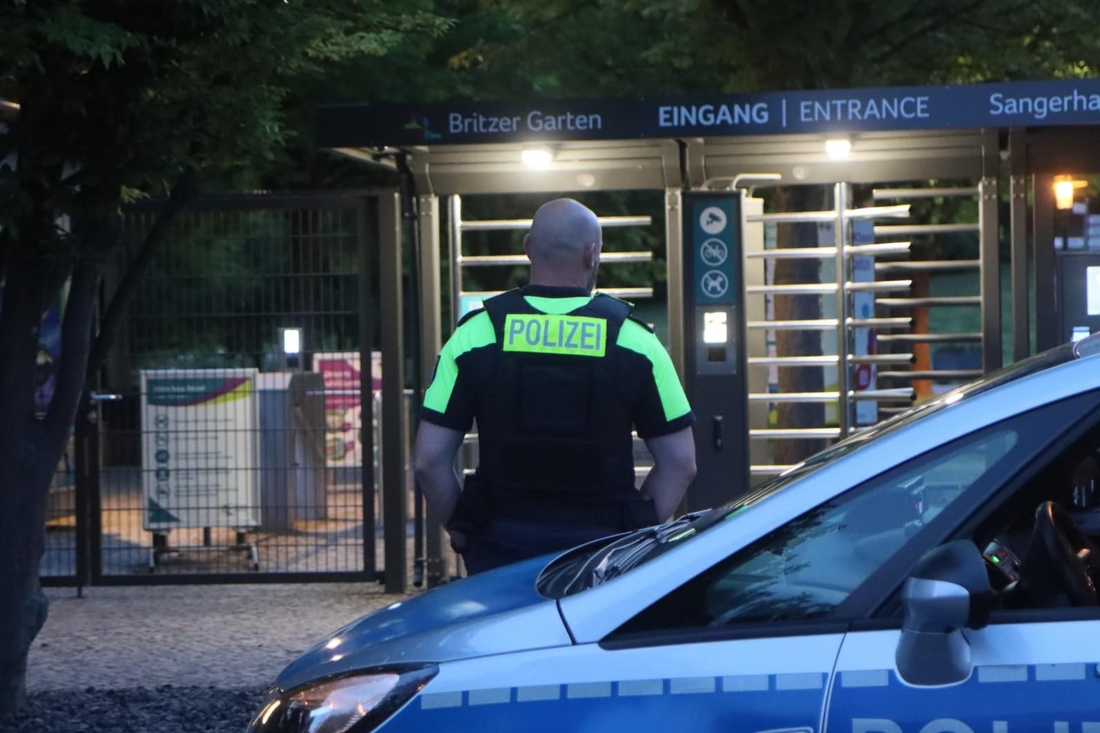 Ein Polizeibeamter steht vor einem Streifenwagen am Britzer Garten in Neukölln: Die Suche nach dem Kind konnte gegen 23 Uhr eingestellt werden.