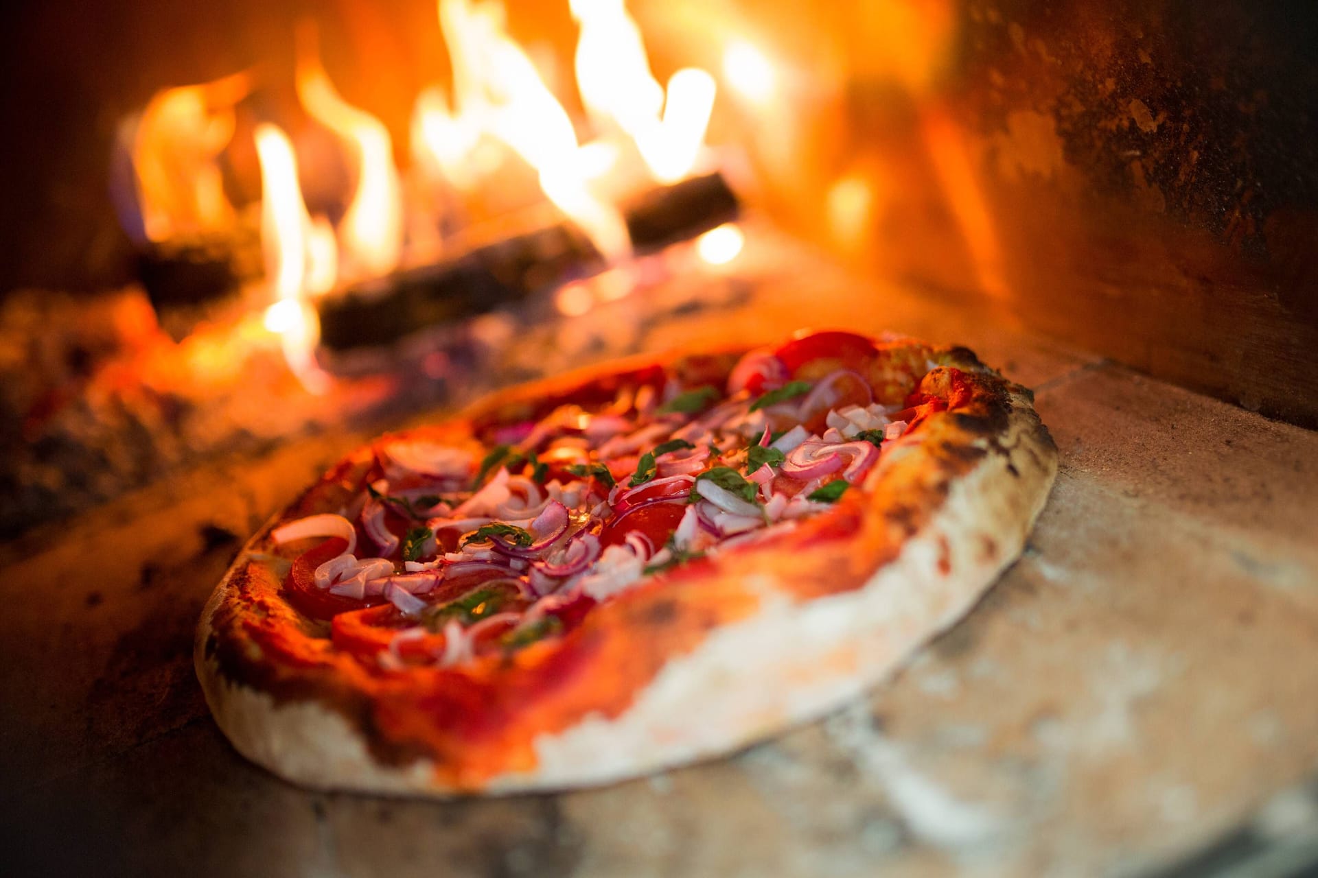 Ein Pizzabäcker schiebt eine Pizza in den Ofen (Symbolbild):