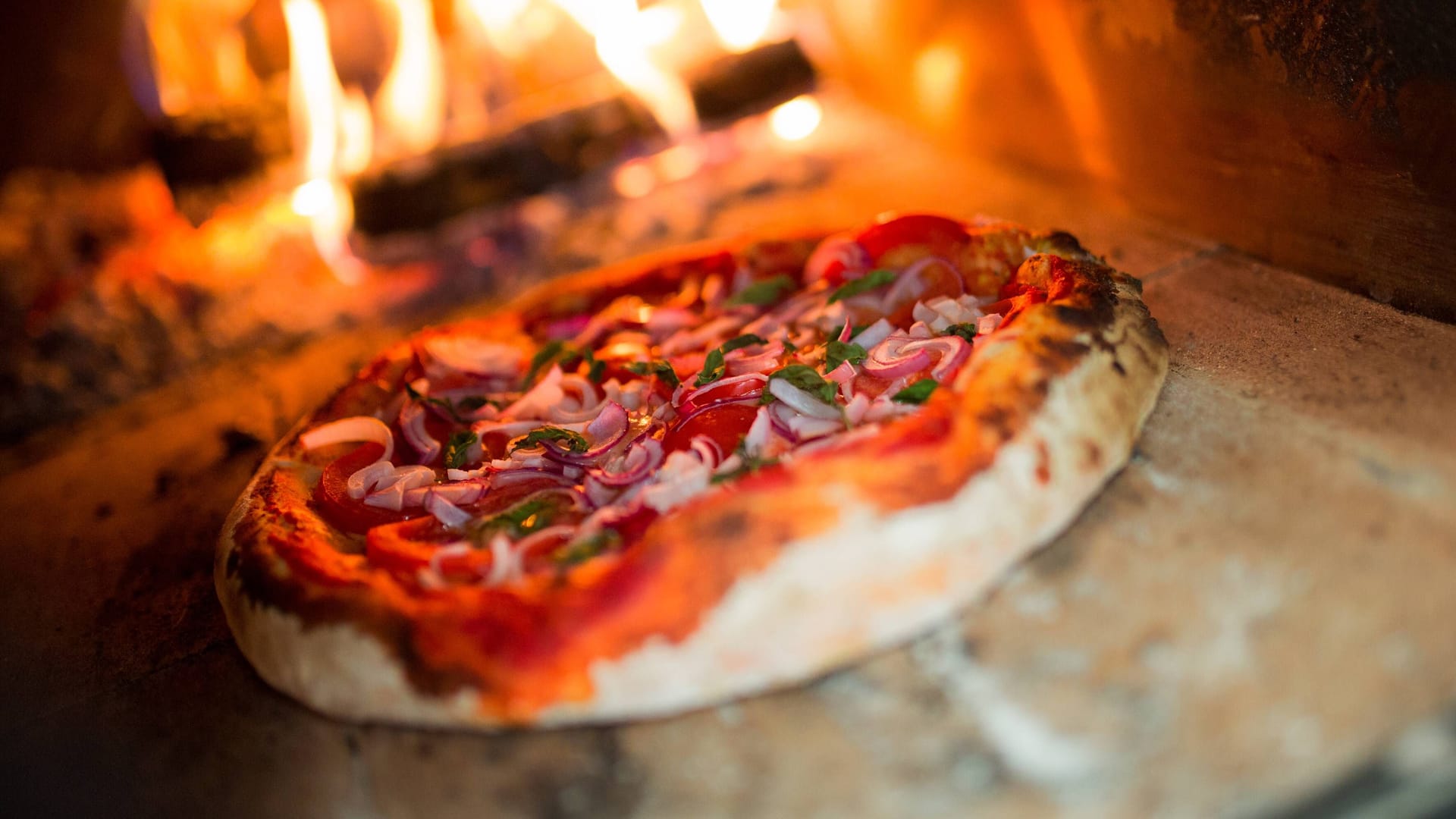 Ein Pizzabäcker schiebt eine Pizza in den Ofen (Symbolbild):