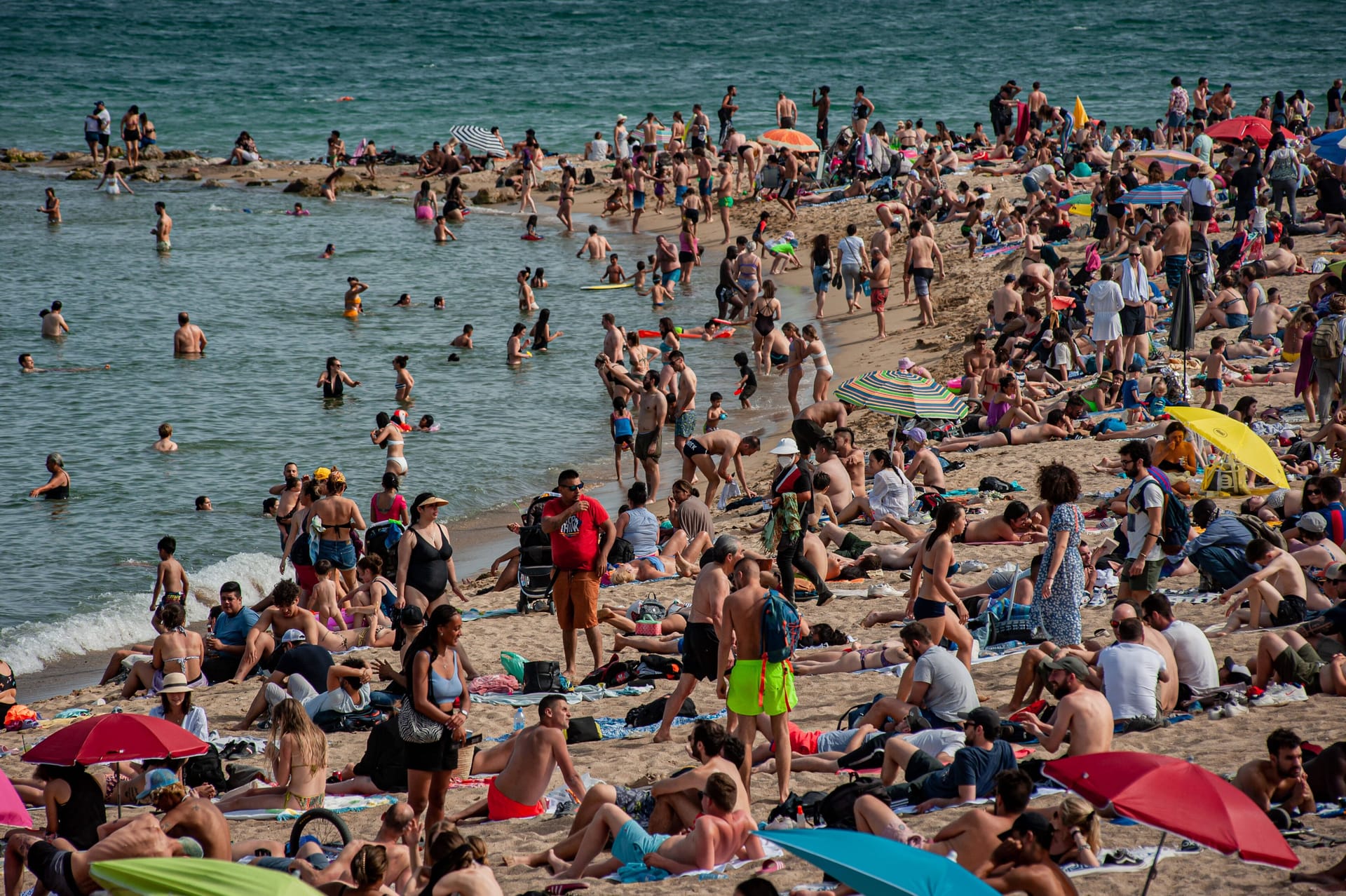 Menschenmassen am Strand von Barcelona: Touristen und Einheimische wollen gleichermaßen den hohen Temperaturen entfliehen und suchen Abkühlung im Mittelmeer.