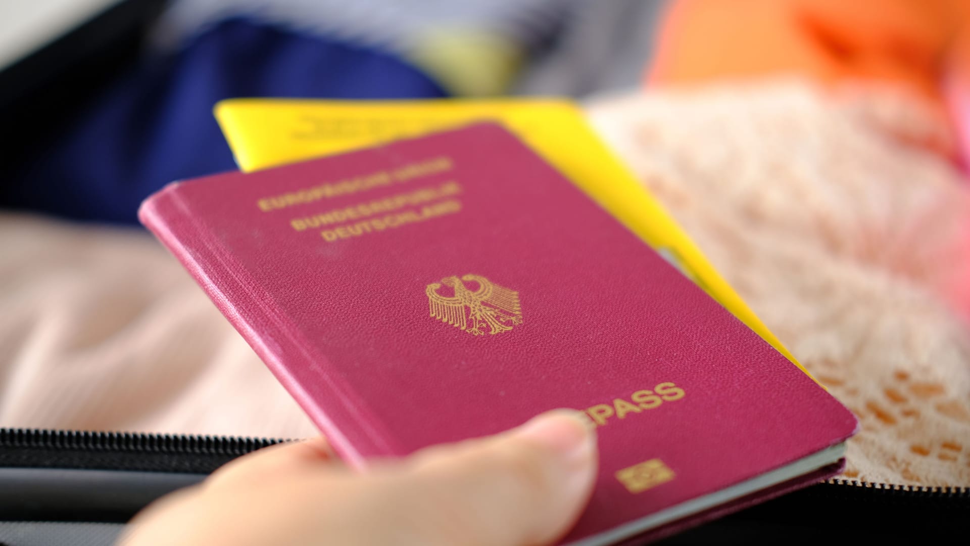 close-up of bright women's passport, covid certificate, things, folded clothes in open silvery suitcase, collecting things for vacation, business trip, an exciting journey, tourism, voyage concept