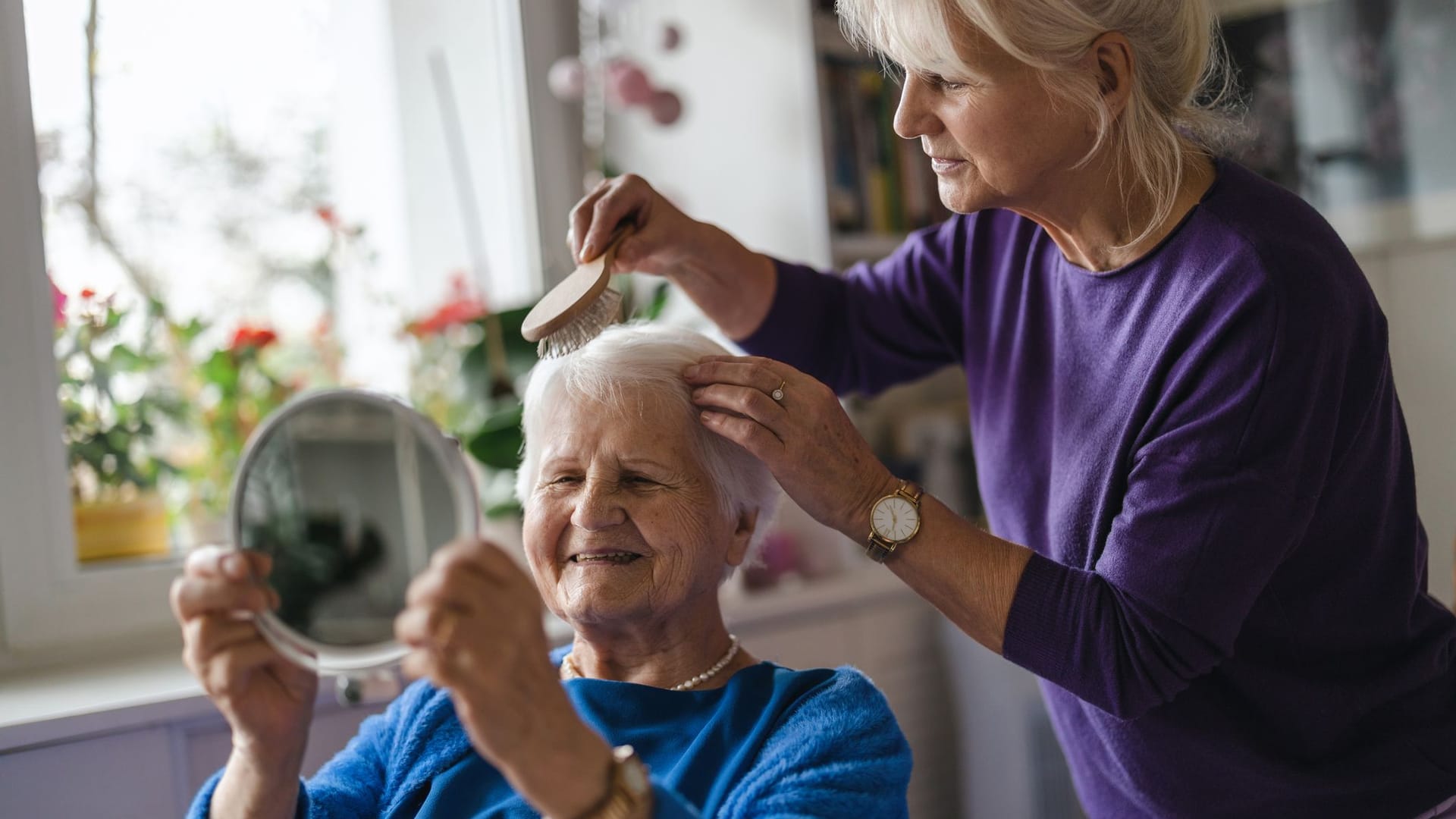 Eine Frau kämmt die Haare einer Pflegebedürftigen: Wenn Angehörige eine Pause von der Pflege benötigen, können sie Verhinderungspflege beantragen.