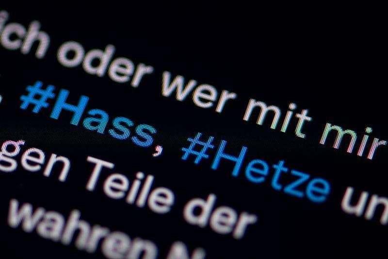 Auf dem Bildschirm eines Smartphones sieht man die Hashtags Hass und Hetze in einem Post auf Twitter (heute X): Die Polizei geht gegen die Verfasser von Hass-Nachrichten bundesweit vor.