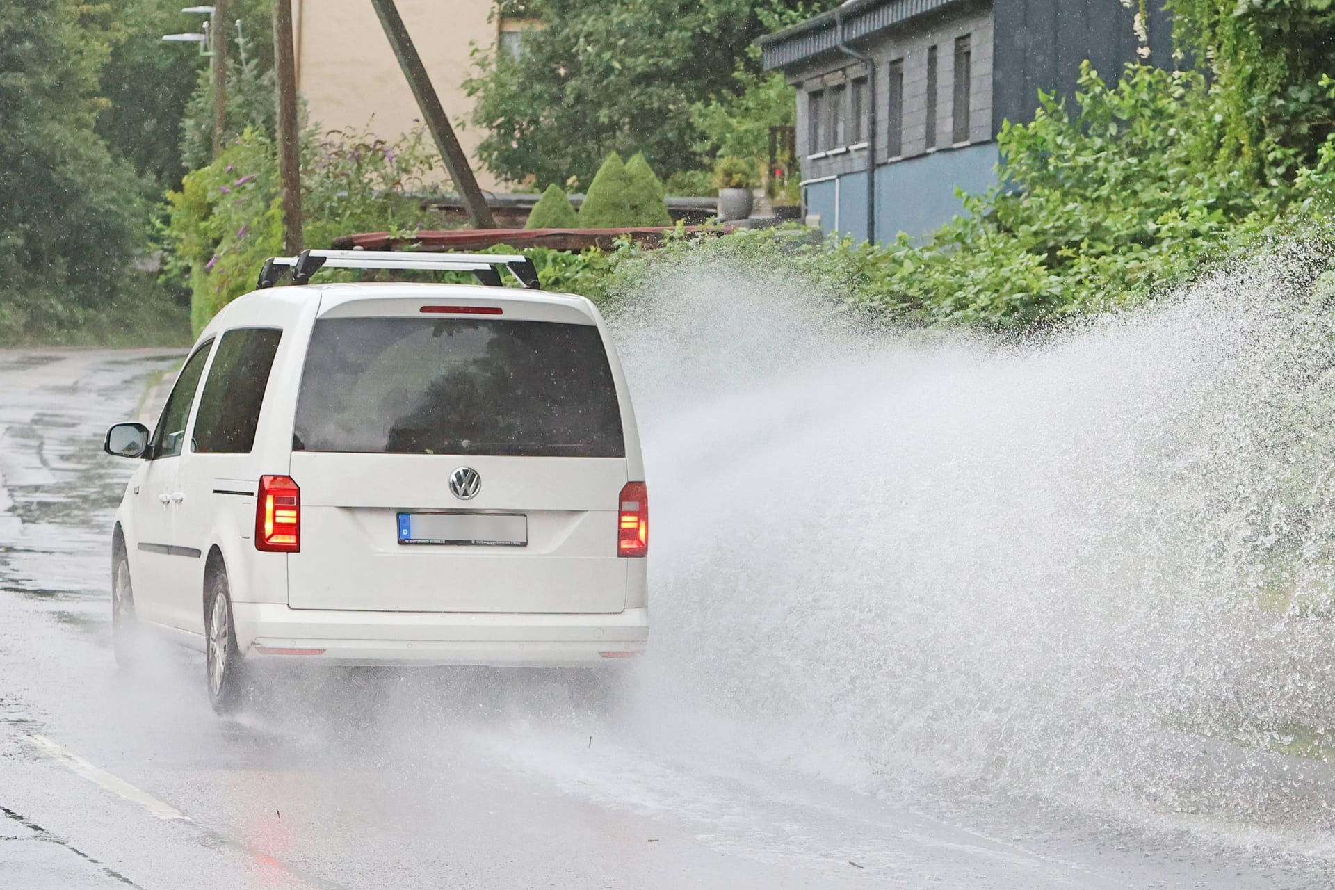 Ein Auto fährt durch strömenden Regen (Symbolbild): In Köln und der Region werden noch bis Mittwoch schwere Unwetter mit Hagel erwartet.