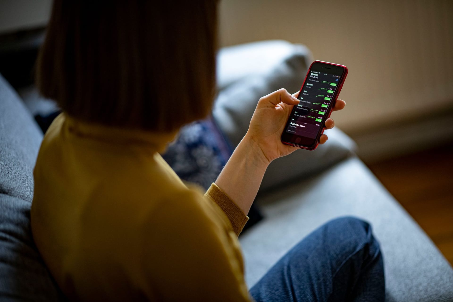 Eine Frau ruft Aktienkurse auf einem Smartphone auf Eine Frau ruft Aktienkurse auf einem Smartphone auf