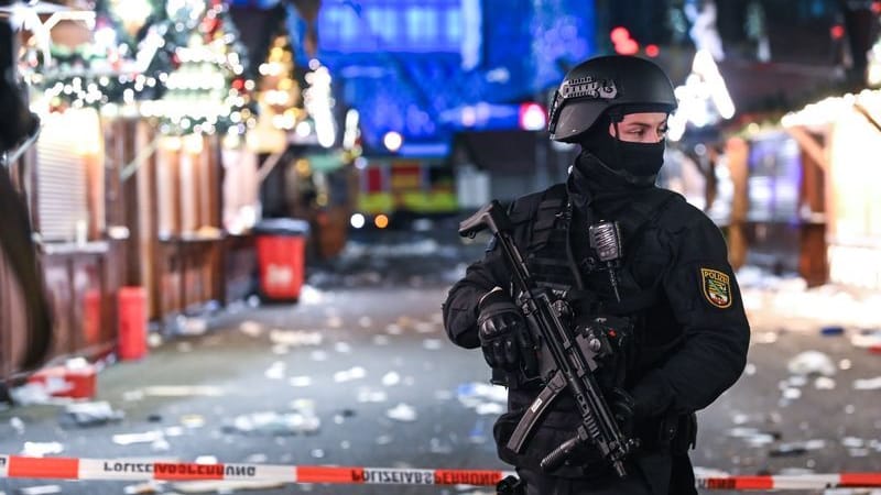 Ein schwer bewaffneter Polizist auf dem verwüsteten Weihnachtsmarkt in Magdeburg (Archivbild): Der mutmaßliche Attentäter muss zum dritten Mal verlegt werden.
